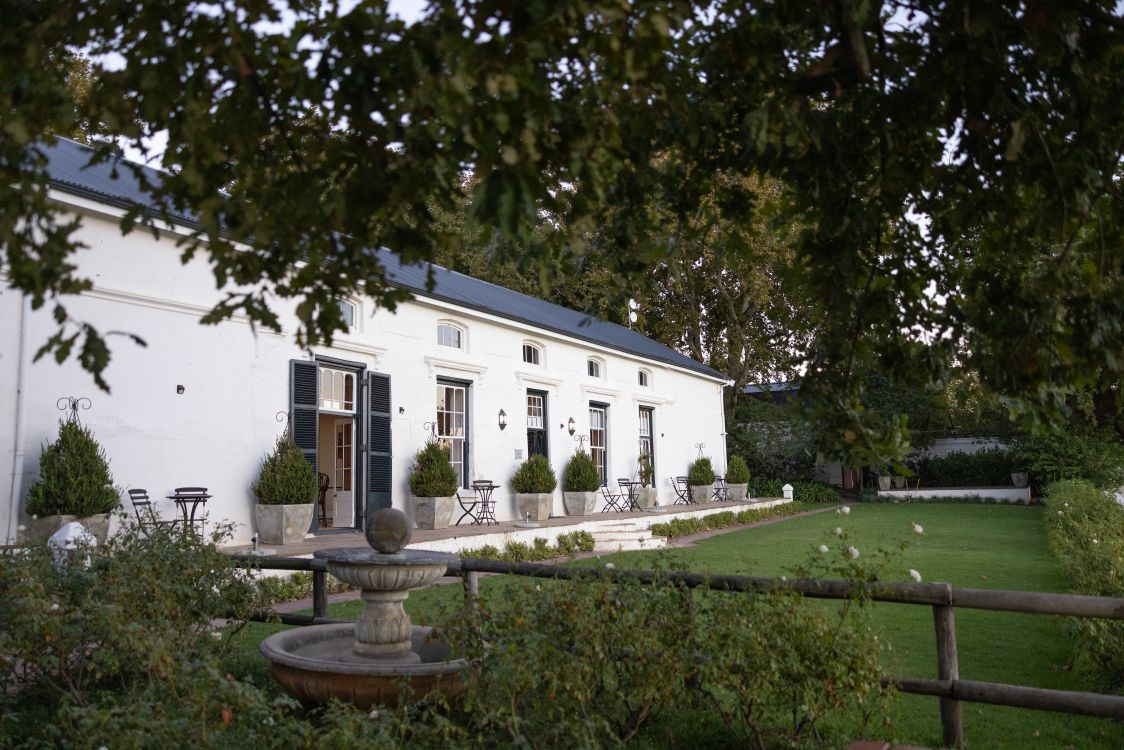 Gebäude auf dem Gelände des Weinguts Under Oaks in Südafrika mit gepflegtem Garten und klassischer Architektur.