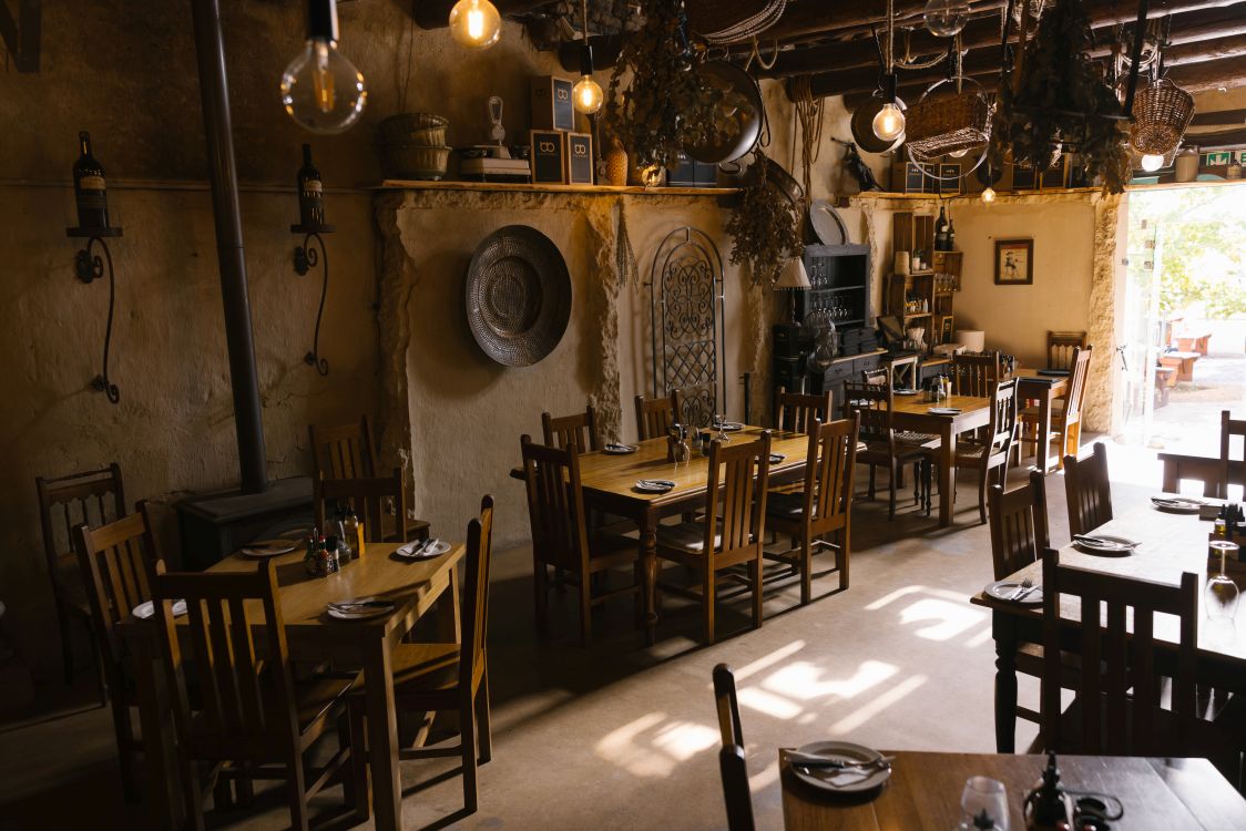 Rustikaler Innenraum der Pizzeria auf dem Weingut Under Oaks mit Holztischen, warmem Licht und gemütlichem Ambiente.